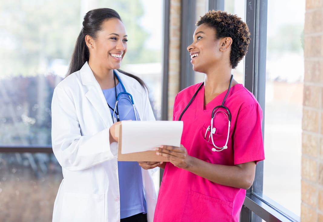 Two medical professionals reviewing a chart with smiles on their faces.